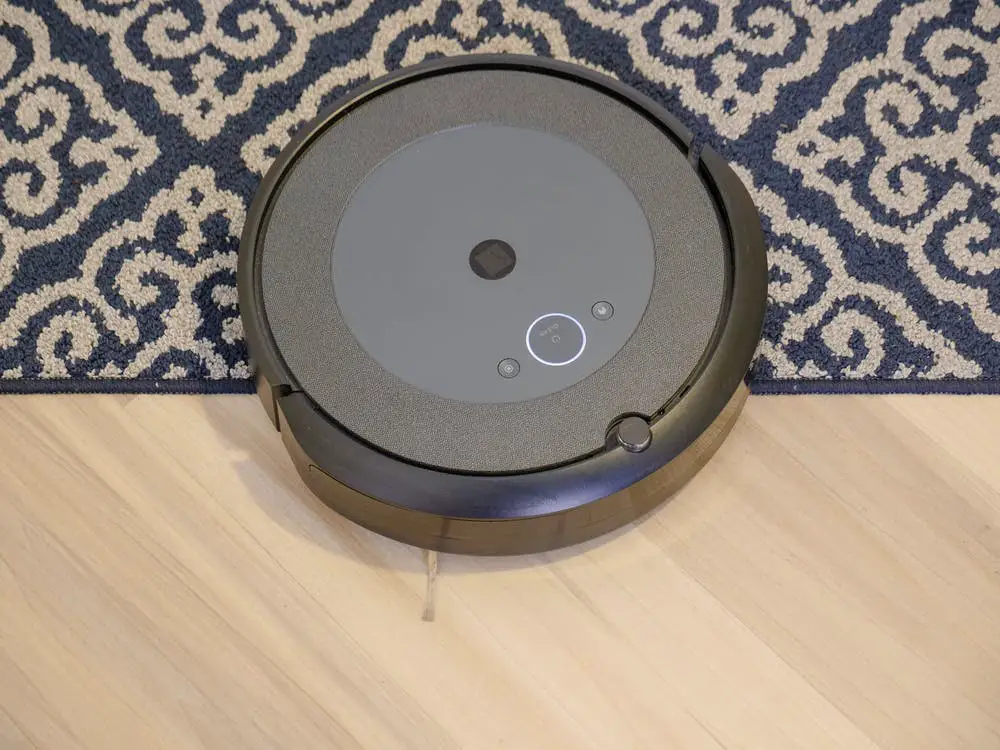A Roomba half on a carpet